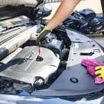 SUV with open hood while two people check the oil level in daylight